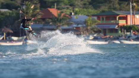 Young-man-makes-trick-jump-on-kiteboard-by-Carribean-sea-coast,-slomo