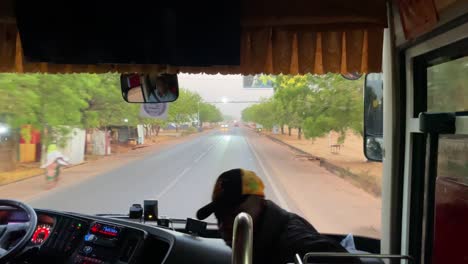 bus-driving-in-african-village-road-to-Wulugu,-asphalted-concrete-road-with-no-traffic