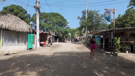 Caminando-En-Primera-Persona-Por-Una-Carretera-Rural-De-Un-Pequeño-Pueblo-Con-Gente-Cruzando-Y-Tiendas-Locales-En-Palomino