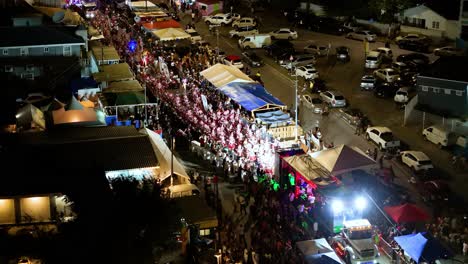Drone-ascends-as-thick-crowd-of-people-in-red-costumes-dance-in-parade-at-night
