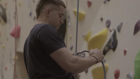 Man-belaying-climber-on-colorful-indoor-climbing-wall