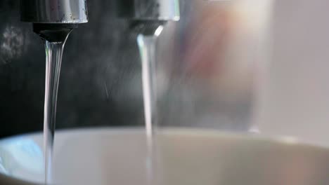 Close-up-of-Italian-Coffee-machine-with-hot-water-and-steaming-black-coffee