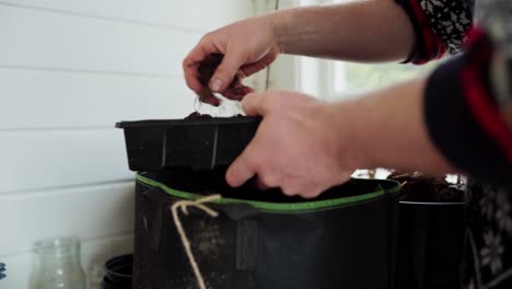 Cropped-View-Of-A-Person-Putting-Loam-Soil-In-A-Seedlings-Disposable-Pot