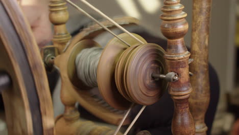Closeup-view:-Woman-begins-to-spin-wool-into-yarn-on-spinning-wheel