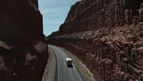 Camper-van-truck-drive-past-massive-Utah-desert-walls-in-sunlight