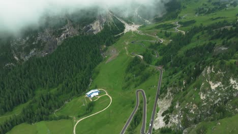 Luftperspektive-Des-Grödner-Passes,-Drohne-Steigt-Durch-Die-Wolken-Auf-Und-Gibt-Den-Blick-Auf-Kurvenreiche-Straße-Mit-Autos-Darunter-Frei