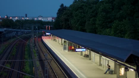 Twilight-scene-at-a-suburban-train-station-with-a-lone-passenger-waiting