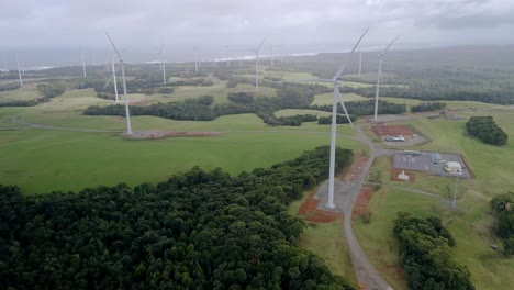 Reverse-drone-shot-of-rotating-wind-turbines-on-Tasmanian-clean-energy-wind-farm,-Australia