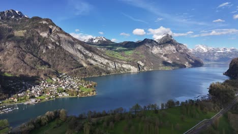 Breathtaking-aerial-view-of-Walensee,-Weesen,-showing-the-vibrant-village-by-the-serene-blue-lake,-nestled-between-rugged-mountains