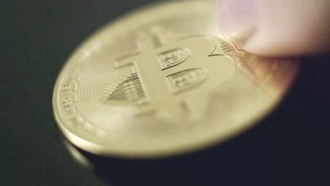 Close-up-bitcoin-coin-studio-golden-finger-shows-crypto-physical-money-business-digital-investment-concept