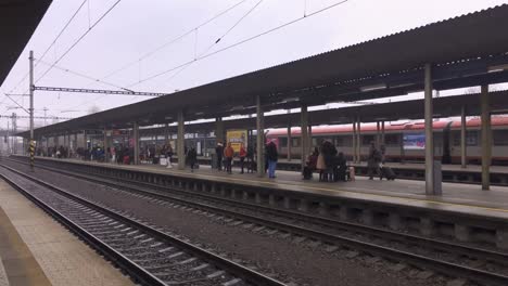 Ostrava-Svinov-train-station-with-platforma-full-of-people-in-foggy-day,-panning-shot