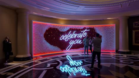 Couple-Taking-Photo-In-Front-Of-Large-Celebrate-You-Wall-Inside-The-Venetian-Hotel-In-Las-Vegas
