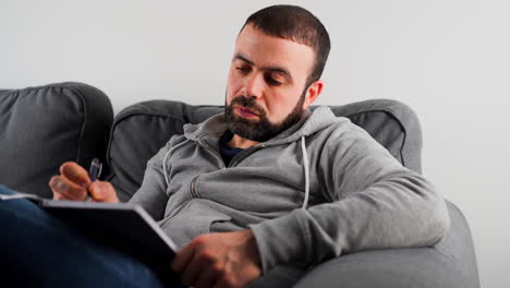 A-Middle-Eastern-Caucasian-Man-Writing-Notes-In-His-Journal---Close-Up