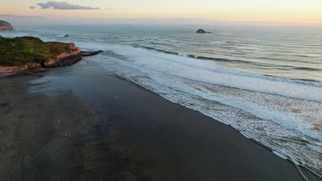 Olas-Chapoteando-En-La-Playa-De-Muriwai-Al-Atardecer-Con-La-Isla-De-Oaia-En-La-Distancia