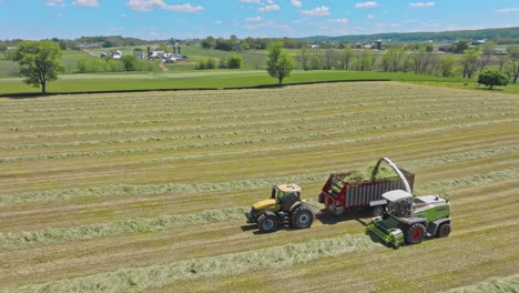 A-CLAAS-Tractors-work-in-harmony,-baling-hay-as-the-day-wanes,-transforming-fields-into-neatly-organized-lines,-under-azure-skies
