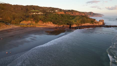 Menschen-Am-Sandstrand-Von-Muriwai-Bei-Sonnenaufgang-Am-Ufer-Der-Maukatia-Bay-In-Neuseeland