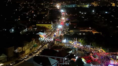 Shimmering-lights-sparkle-and-flash-during-night-time-parade-for-Carnaval,-aerial-orbit
