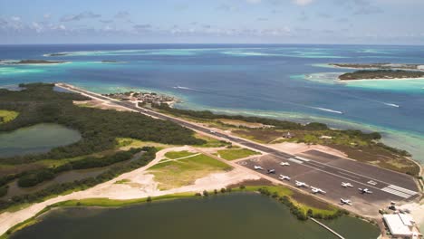 Los-roques-airstrip-with-parked-planes-and-turquoise-sea,-aerial-view