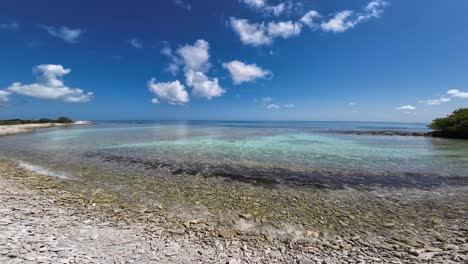Bright-day-at-Playa-de-Coral,-Los-Roques-with-clear-turquoise-waters-and-fluffy-clouds