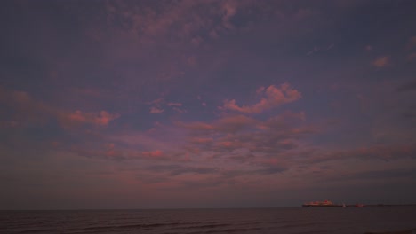 Zeitraffer-Des-Sonnenuntergangshimmels-Am-Wattenmeer-Bei-Hooksiel,-Norddeutschland-Mit-Ziehenden-Wolken-Und-Einem-Containerschiff