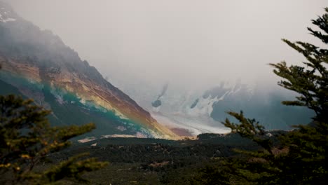 Caminata-Argentina,-Vista-De-El-Chalten,-Cerro-Torre-A-Través-De-árboles,-Hermosa-Cordillera-Cubierta-De-Nieve,-Arco-Iris,-Brumoso,-Toma-De-Establecimiento