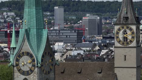 Linksbewegte-Parallaxenaufnahme-Der-Uhrentürme-Der-Züricher-Altstadt-Bei-Sonnigem-Wetter-Mit-Der-Skyline-Von-Zürich-Im-Hintergrund