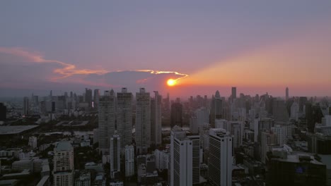 Sunrise-casting-a-vibrant-halo-over-Bangkok’s-skyline,-showcasing-a-mix-of-modern-skyscrapers-and-urban-sprawl
