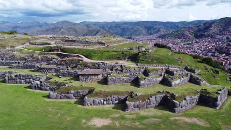 Descenso-Aéreo-Sobre-Muros-De-Piedra-En-Terrazas-Y-Césped-Con-Vistas-A-Cusco,-Perú