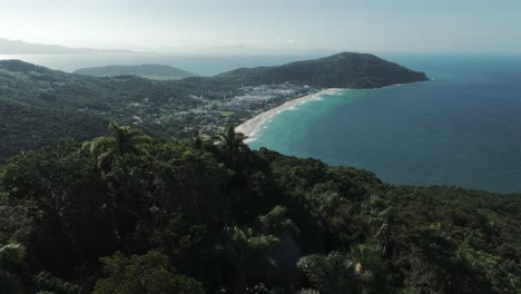 Aerial-image-emerges-from-behind-a-mountain,-unveiling-the-breathtaking-Praia-Brava-Beach-in-Florianopolis,-Santa-Catarina,-Brazil