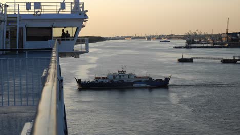 A-small-ferry-with-passengers-and-cars-passes-by-a-large-ship
