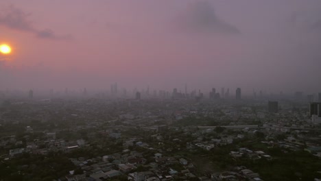 Nebelige-Bangkok-Stadt-Mit-Schwachem-Sonnenuntergang,-Der-Durchscheint,-Rückwärtsaufnahme-Einer-Drohne