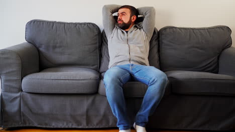 Tired-Caucasian-Man-Yawning-While-Sitting-In-A-Couch-At-Home