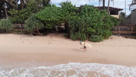 Sportlicher-Männlicher-Surfer-Läuft-Am-Sandstrand-In-Sri-Lanka-Entlang