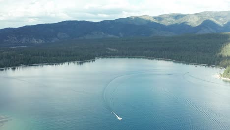 Imágenes-De-Seguimiento-De-Drones-De-Un-Barco-Navegando-En-Un-Lago-De-Gallineta-Nórdica-Rodeado-De-Agua-Azul