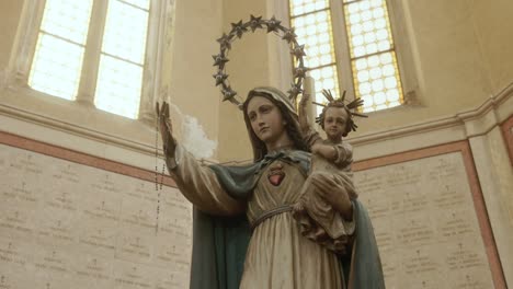 Estatua-De-La-Virgen-Con-El-Niño-Y-El-Rosario-Dentro-Del-Templo-Del-Osario-En-Bassano-Del-Grappa,-Italia