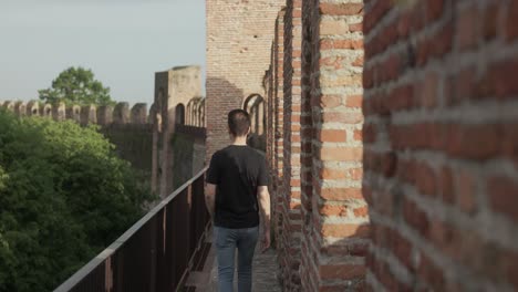 A-Man-Is-Walking-On-The-Parapet-Walkway-Of-The-Medieval-Wall-Of-Cittadella,-Italy
