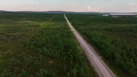 Drone-flying-backwards-in-front-of-a-RV-driving-in-boreal-nature-of-the-arctic-north