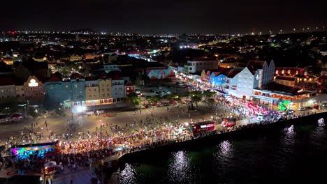 Retroceso-Aéreo-Mientras-La-Luz-Brilla-En-El-Agua-De-La-Gran-Marcha-Del-Carnaval-Por-La-Noche