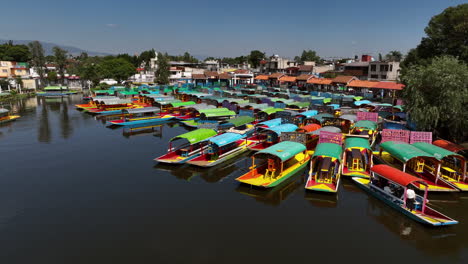 Drone-flying-over-Trajinera-boats-docked-at-the-Xochimilco-Lake,-in-sunny-Mexico
