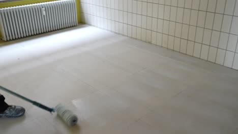 Construction-worker-watering-floor-with-clue-to-put-and-lay-carpet