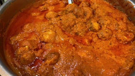 Indian-cuisine---Cinematic-shot-of-Kashmiri-aloo-kofta-made-of-potatoes-in-red-gravy-in-a-metal-bowl