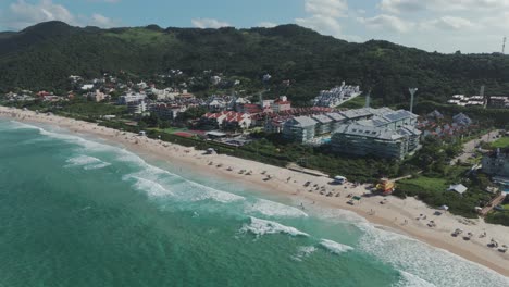 A-drone-advances-over-Praia-Brava-in-Florianopolis,-capturing-its-stunningly-clear-waters-and-luxurious-condominiums