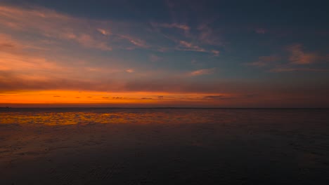 Time-lapse-of-the-Wadden-Sea-at-Schillig-in-North-Germany-by-sunset-with-clouds-moving-and-reflection