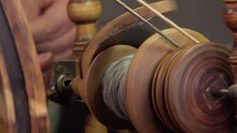 Close-up-spinning-wheel-bobbin-spins-wool-into-yarn,-traditional-craft