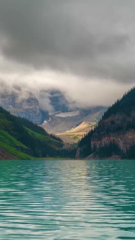 Timelapse-Vertical-De-4k,-Aguas-Cristalinas-Del-Lago-Louise-Y-Nubes-Moviéndose-Sobre-Los-Picos-Del-Parque-Nacional-Banff,-Canadá