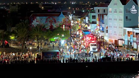 Gran-Marcha-Parade-wraps-around-waterfront-buildings-at-night,-aerial-overview