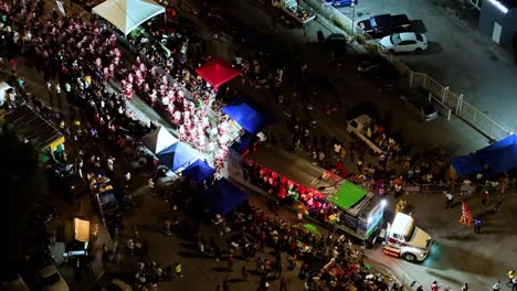 Leuchtende-Lichter-Beleuchten-Den-Weg-Für-Die-Karnevalskünstler-Bei-Der-Parade-In-Der-Nacht,-Luftaufnahme