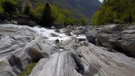 Cerca-De-Una-Cascada,-Kayakista-En-El-Arroyo-Salvaje-Cerca-De-Lavertezzo,-Valle-De-Verzasca-Entre-Grandes-Piedras