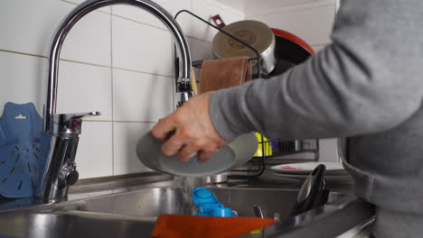 Unrecognizable-Man-Washing-Dishes-In-The-Kitchen