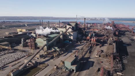 An-industrial-steel-mill-in-hamilton,-ontario,-with-plumes-of-steam-and-machinery,-aerial-view